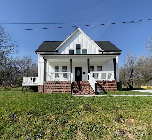 bungalow-style house featuring roof with shingles, a porch, board and batten siding, and a front yard