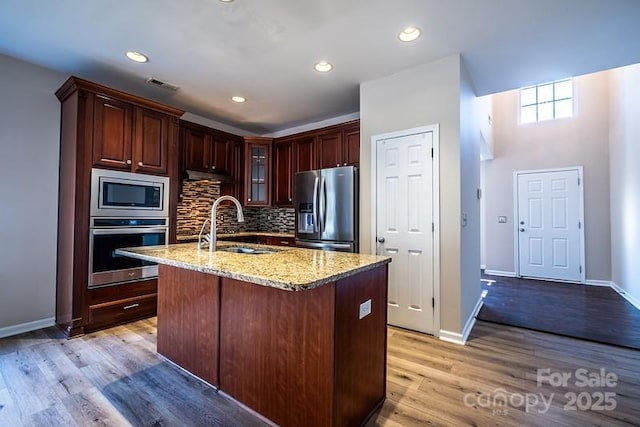 kitchen with light wood finished floors, visible vents, backsplash, appliances with stainless steel finishes, and a sink