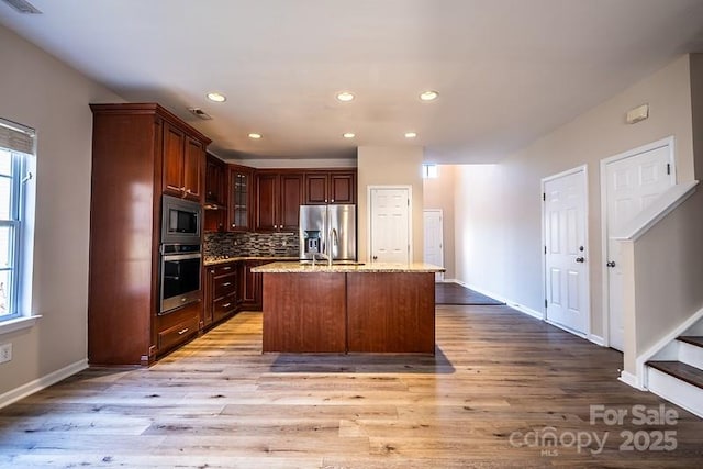 kitchen with glass insert cabinets, tasteful backsplash, appliances with stainless steel finishes, and light wood-style flooring