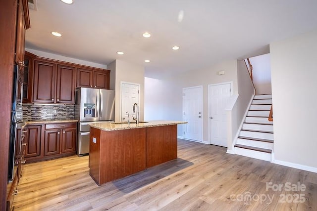 kitchen featuring light wood-type flooring, backsplash, a sink, and stainless steel fridge with ice dispenser