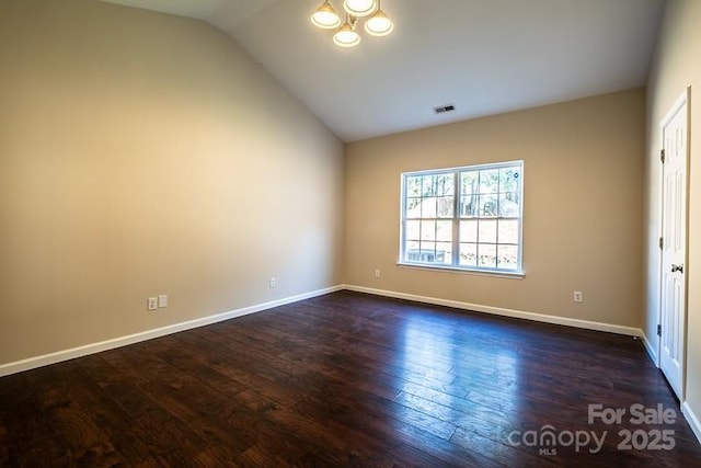 spare room with vaulted ceiling, dark wood-style floors, visible vents, and baseboards