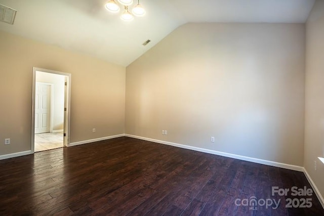 spare room with lofted ceiling, baseboards, visible vents, and wood finished floors