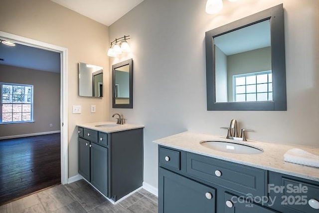 bathroom featuring baseboards, two vanities, and a sink