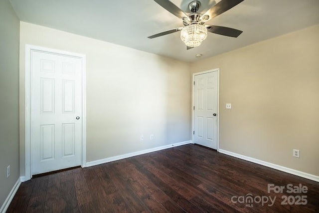 empty room featuring baseboards, dark wood finished floors, and a ceiling fan