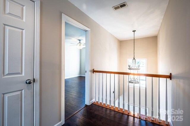 hallway featuring dark wood-style flooring, visible vents, and baseboards