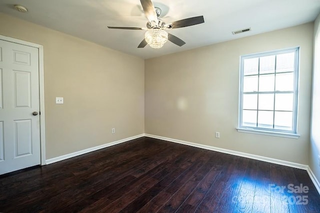 spare room featuring ceiling fan, dark wood-type flooring, visible vents, and baseboards