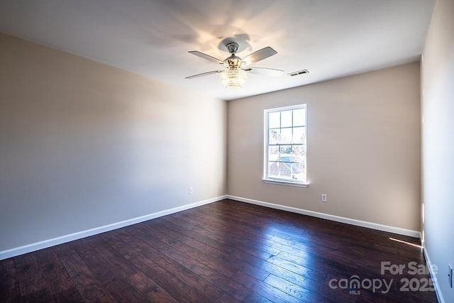 empty room with a ceiling fan, wood-type flooring, visible vents, and baseboards