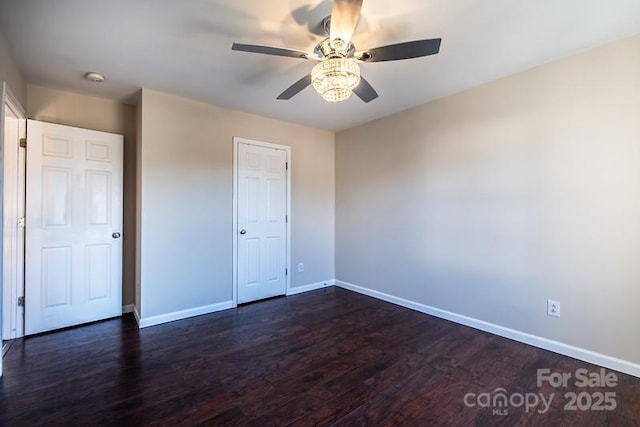 unfurnished bedroom with dark wood-style flooring, ceiling fan, and baseboards