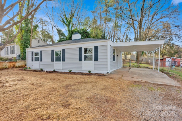 manufactured / mobile home featuring driveway, a chimney, fence, a front lawn, and a carport