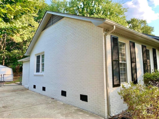 view of property exterior with crawl space, a patio area, fence, and brick siding