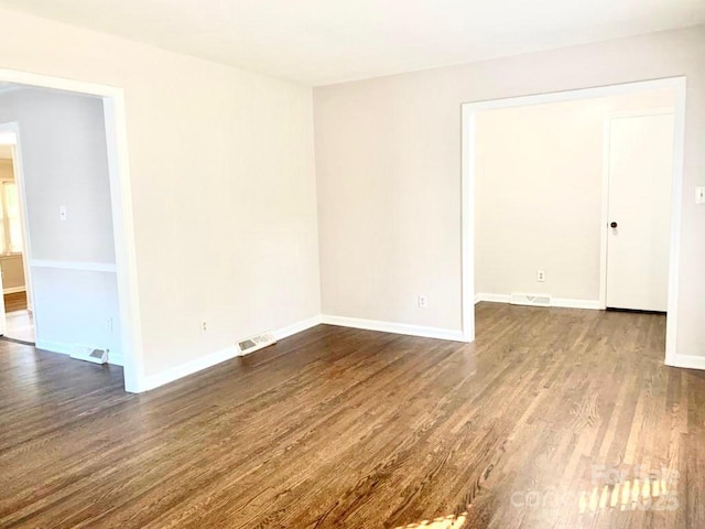 unfurnished room featuring baseboards, visible vents, and wood finished floors