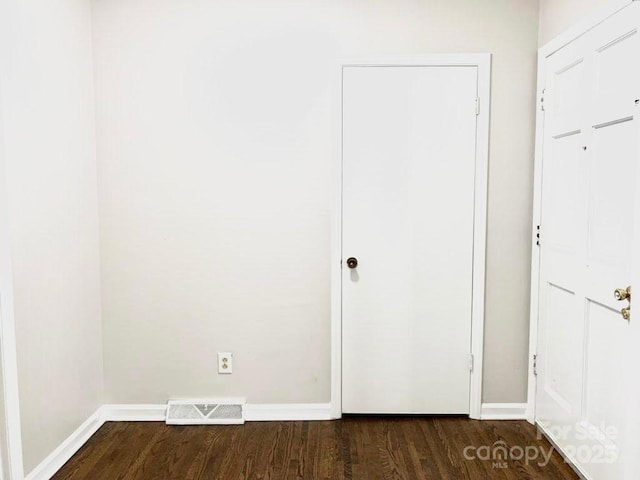 unfurnished bedroom featuring dark wood-style floors, visible vents, and baseboards