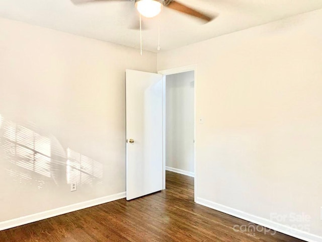 empty room featuring dark wood-style floors, ceiling fan, and baseboards