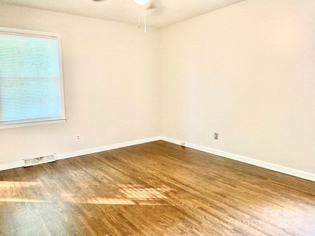 spare room with baseboards, visible vents, ceiling fan, and wood finished floors