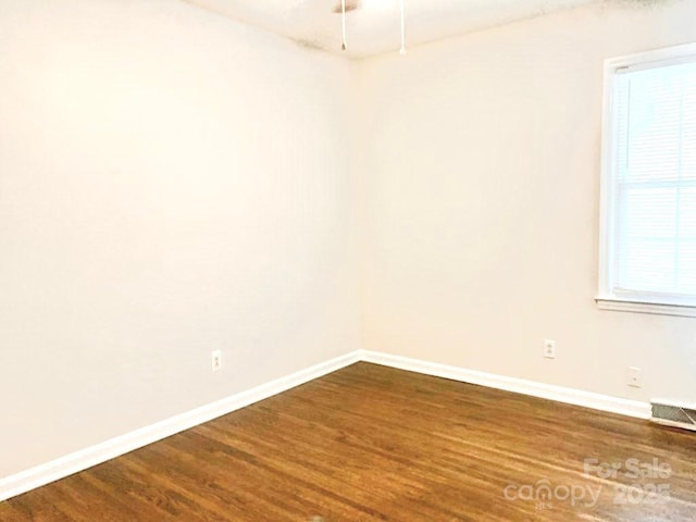 spare room with visible vents, baseboards, and wood finished floors