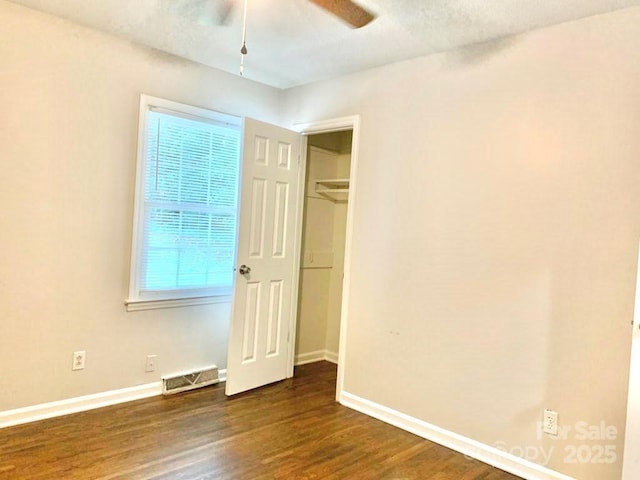 unfurnished bedroom featuring ceiling fan, dark wood-type flooring, visible vents, and baseboards