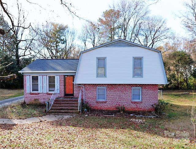 view of front of house featuring brick siding and a gambrel roof