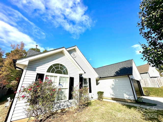 view of front of home with fence, a front lawn, and roof with shingles