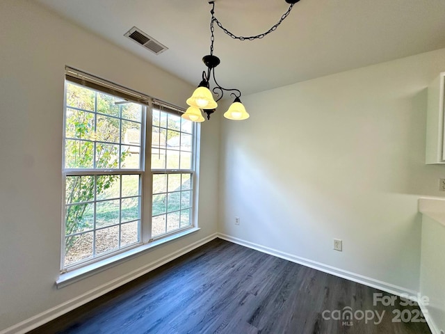 unfurnished dining area featuring baseboards, visible vents, dark wood finished floors, and a chandelier