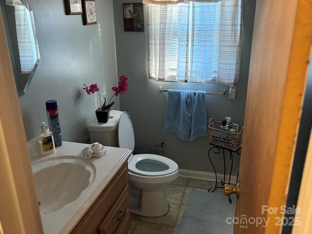 half bathroom featuring baseboards, vanity, and toilet