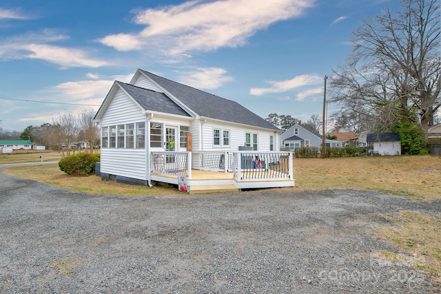 view of front of property with a wooden deck and roof with shingles