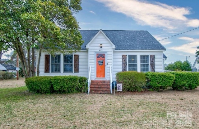 view of front of house featuring a shingled roof and a front yard