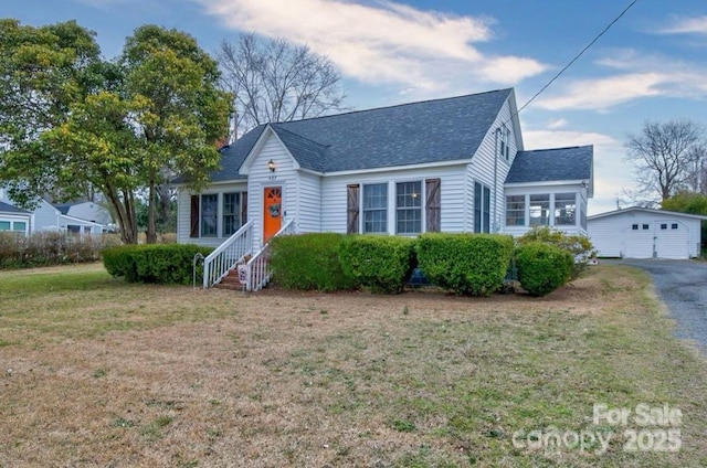 view of front facade featuring a front lawn, entry steps, roof with shingles, a garage, and an outdoor structure