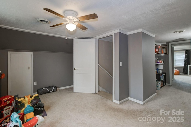 interior space with visible vents, a ceiling fan, a textured ceiling, baseboards, and light colored carpet