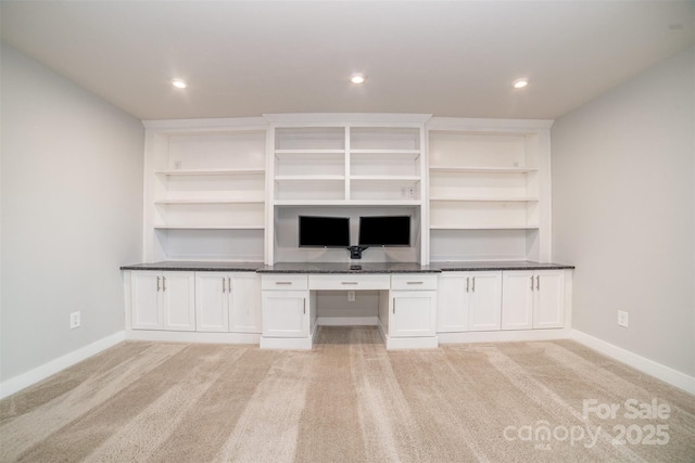 unfurnished living room with light colored carpet, built in study area, baseboards, and recessed lighting