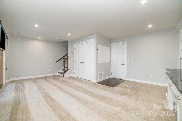 interior space with recessed lighting, stairs, baseboards, and light colored carpet