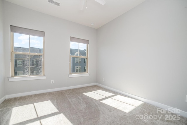 carpeted spare room with plenty of natural light, visible vents, vaulted ceiling, and baseboards