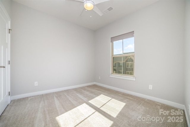 spare room with carpet floors, a ceiling fan, visible vents, and baseboards