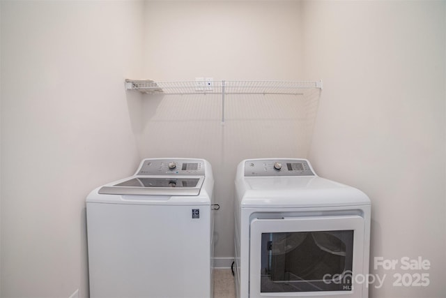 washroom featuring laundry area, washing machine and dryer, and baseboards