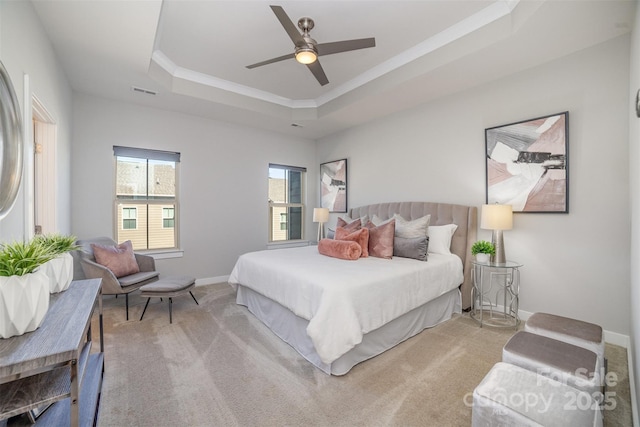 carpeted bedroom featuring baseboards, visible vents, a tray ceiling, and ceiling fan