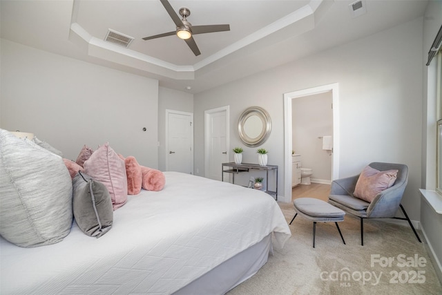 bedroom featuring visible vents, a tray ceiling, baseboards, and ensuite bathroom