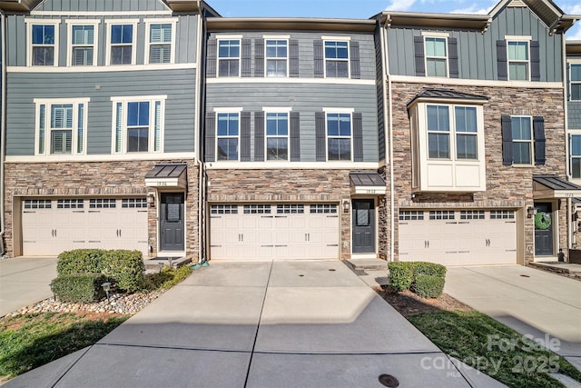 multi unit property with stone siding, an attached garage, board and batten siding, and driveway