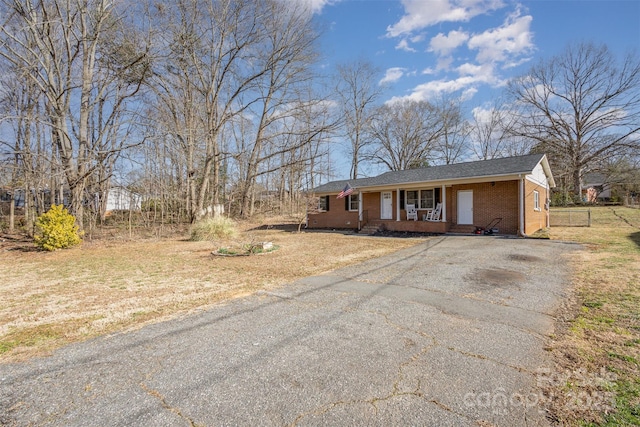 ranch-style house with covered porch, aphalt driveway, and brick siding