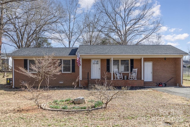 ranch-style home featuring roof with shingles, a porch, crawl space, and brick siding