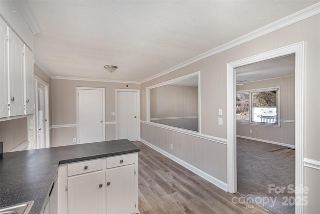 kitchen with a peninsula, dark countertops, white cabinetry, and light wood finished floors