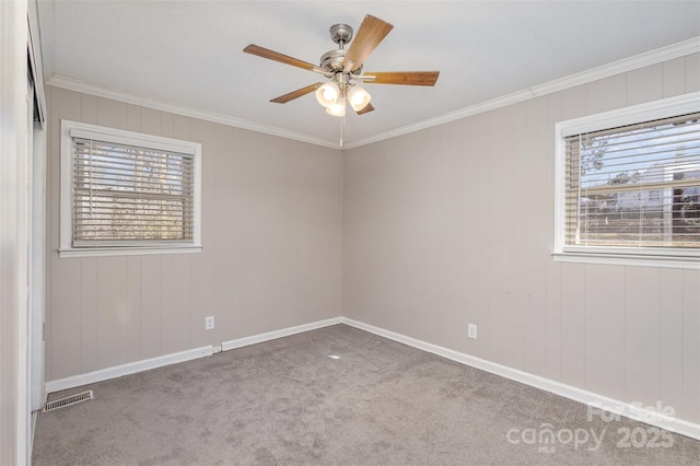 carpeted spare room featuring baseboards, ceiling fan, visible vents, and crown molding