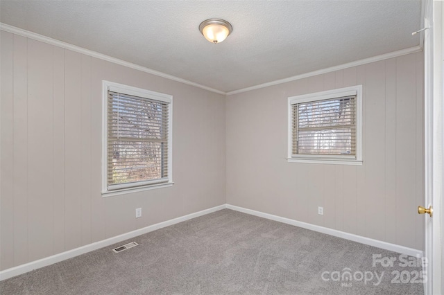 spare room with a textured ceiling, visible vents, baseboards, carpet, and crown molding