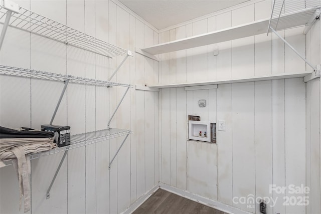 interior space featuring laundry area, wood walls, washer hookup, and dark wood finished floors