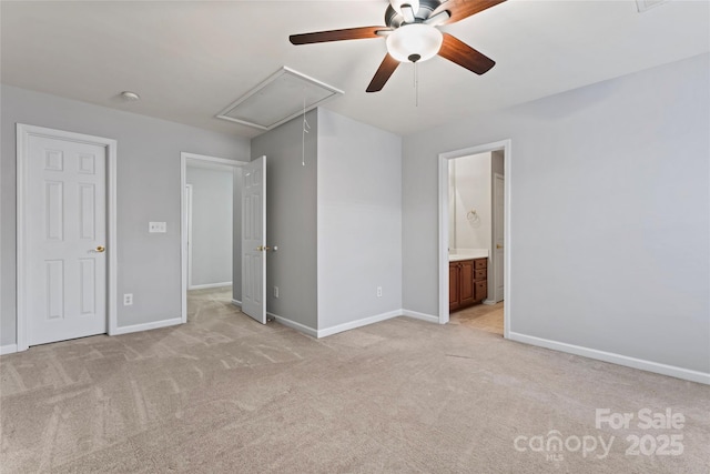 unfurnished bedroom with light colored carpet, ensuite bathroom, attic access, ceiling fan, and baseboards