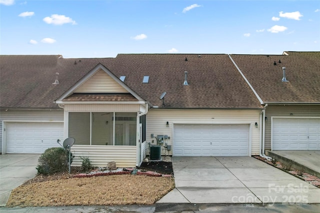 view of property with a sunroom, a shingled roof, cooling unit, and concrete driveway