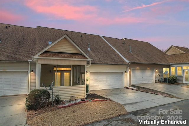 view of property with a garage, concrete driveway, and roof with shingles