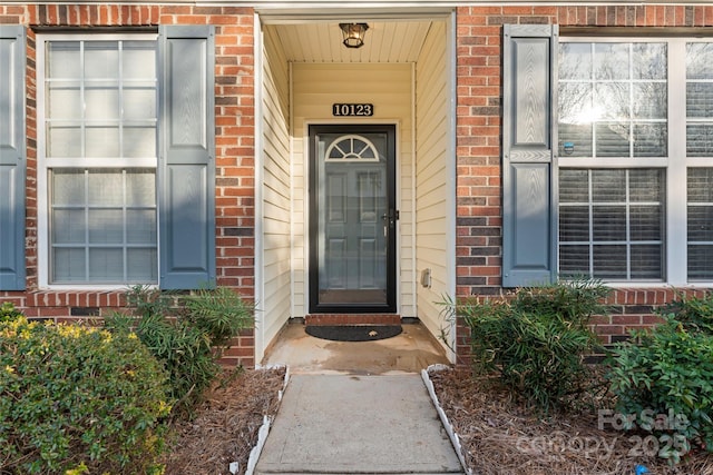 doorway to property featuring brick siding