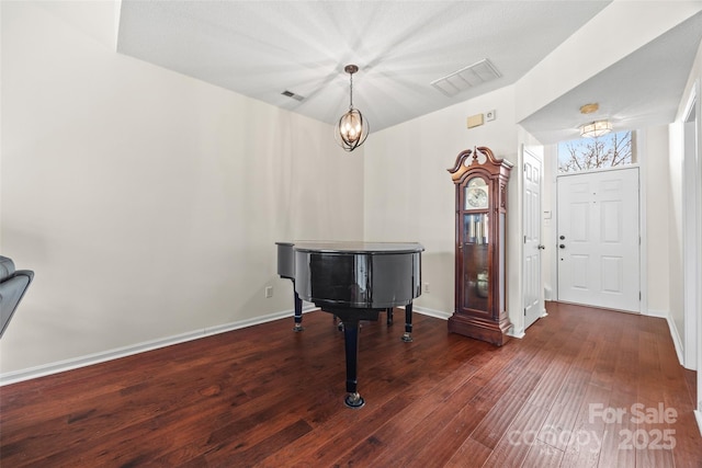 foyer entrance featuring hardwood / wood-style floors, visible vents, and baseboards