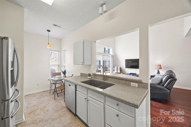 kitchen featuring visible vents, appliances with stainless steel finishes, open floor plan, a sink, and a textured ceiling