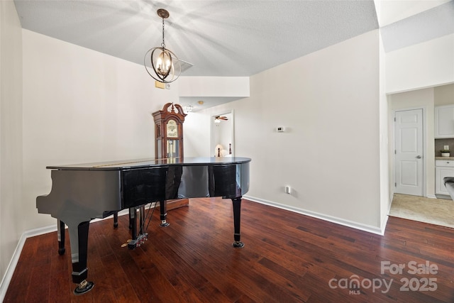 living area with an inviting chandelier, wood-type flooring, and baseboards