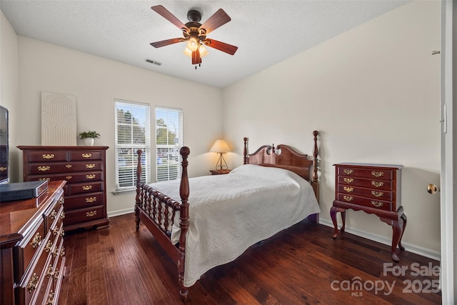 bedroom featuring a textured ceiling, dark wood-type flooring, a ceiling fan, visible vents, and baseboards